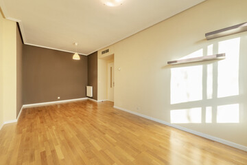 Empty living room with oak hardwood flooring, dark gray painted wall and two others in soft cream color
