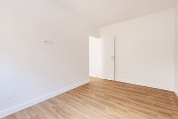 Empty living room with chestnut hardwood floors, plain white painted walls and woodwork