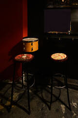 Fototapeta na wymiar Corner of a music venue with a drum and a pair of tall wooden and metal stools