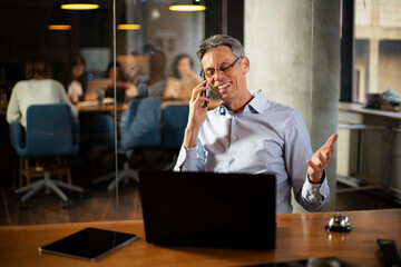 Businessman in office. Handsome man talking on phone at work.