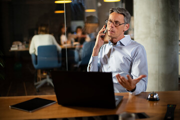 Businessman in office. Handsome man talking on phone at work.