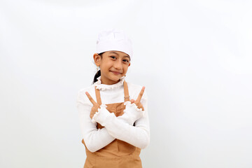 Happy little girl in chef uniform pointing both sides. Isolated on white background