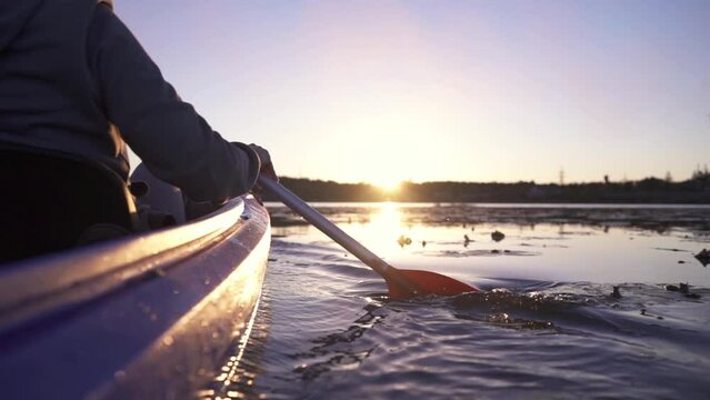 Oar paddles on calm water against the background of sunset rays