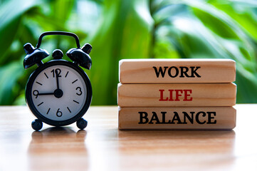 Alarm clock pointing at 9am with work life balance text on wooden blocks. Work life balance concept