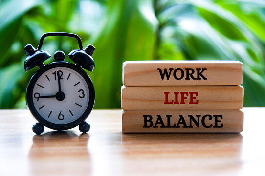 Alarm clock pointing at 9am with work life balance text on wooden blocks. Work life balance concept