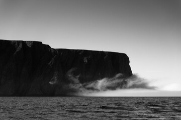 The northernmost tip of Europe large rock cliff of North Cape or Nordkapp on summer day with dramatic sea fog rising on Mageroya island in Finnmark in Northern Norway.