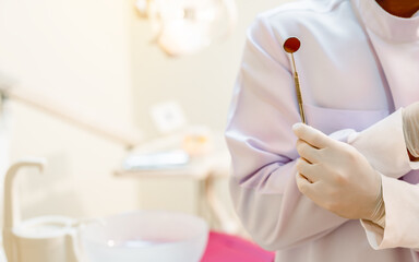 The dentist's hand holds the tooth checker and a mirror for checking and caring for the dentist's...