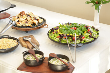 Pratos na mesa com carne na panela e salada lindas de ver.