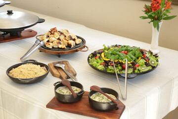 Pratos na mesa com carne na panela e salada lindas de ver.