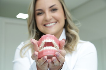 Mulher Dentista mostrando com sorriso os aparelhos utilizados.