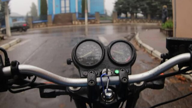 first-person motorcycle ride on wet asphalt in a rainy city and fog.