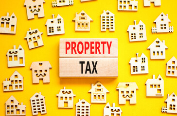 Property tax symbol. Concept words Property tax on wooden blocks. Beautiful yellow table yellow background. House models. Business and property tax concept. Copy space.