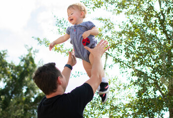 Father throws his happy baby daughter up in the air. Fatherhood. Happy family, happy childhood