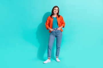 Full length photo of dreamy adorable girl dressed orange shirt looking empty space isolated turquoise color background