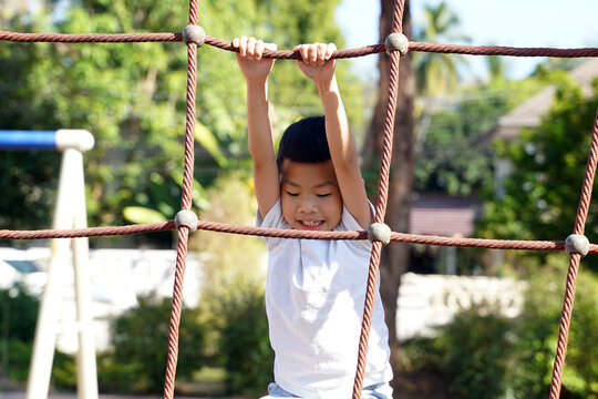 Asian children playing climbing rope net in playground. Concept playground, child development, sports and recreation. Soft and selective focus. 