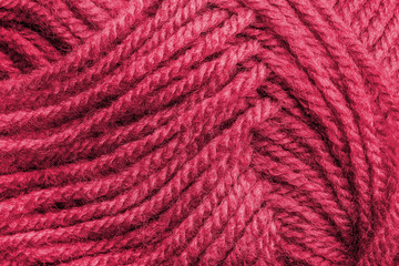 Cropped skein of viva magenta woolen knitting thread texture. Ball of soft woolen yarn closeup. Knitting threads for handicraft and home hobbies background. Color of the year 2023.