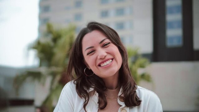 Portrait of young woman smiling and looking at camera with white tooth standing outdoors. Front view of happy teenage girl with positive attitude. High quality 4k footage