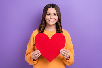 Photo of cheerful friendly girl beaming smile hands hold paper red heart isolated on violet color background