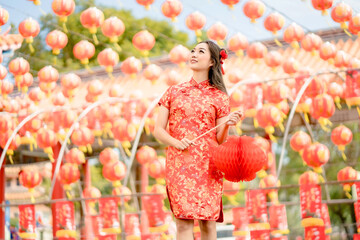 Young lady woman wearing traditional cheongsam qipao costume holding lantern in Chinese Buddhist temple. Celebrate Chinese lunar new year, festive season holiday. Emotion smile