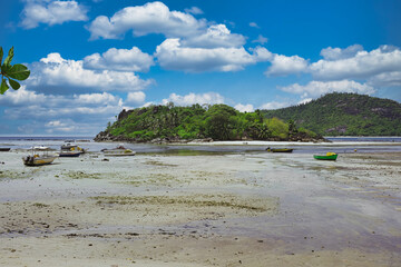 Mahe Seychelles, Port Glaud beach with very low tide, no water blue sky and boats on sands