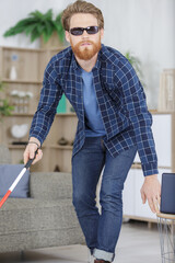 visually impaired man using stick to move around the home