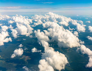 Aerial view from airplane window above green ground. View from the airplane window with beautiful clouds at sunrise © Dmitrii Potashkin