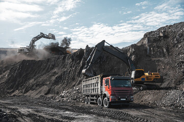 Large quarry dump truck. Big yellow mining truck at work site. Loading coal into body truck....