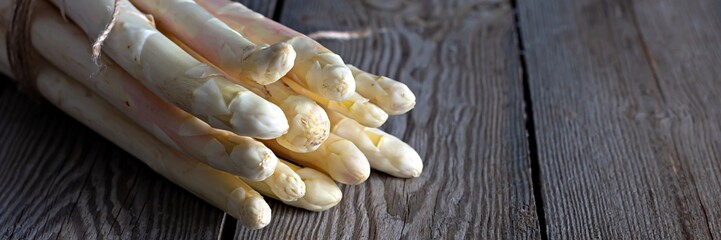 Fresh white asparagus on a wooden background. Photo in low key. Raw food concept.