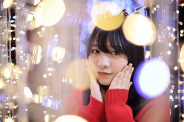 Beautiful Asian young woman with a red sweater with Christmas tree light