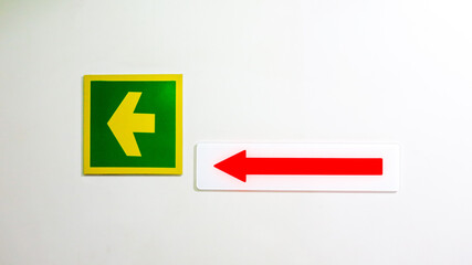 Green yellow left arrow acrylic sign and red arrow on white acrylic sign show us emergency route