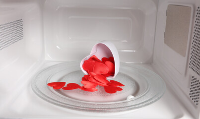Gift box with hearts inside a microwave oven close-up