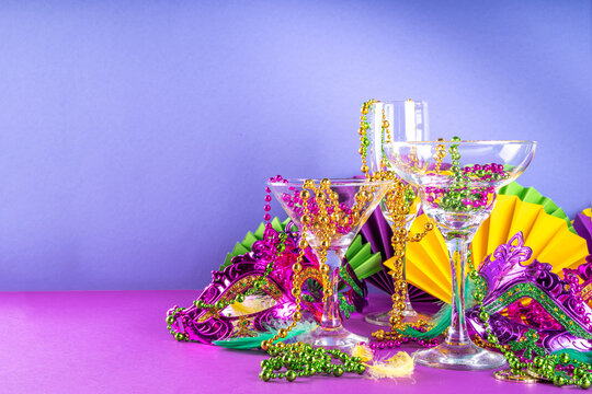 Mardi gras cocktails set. Colorful purple, yellow, green martini champagne wine cocktail glasses for Mardi gras party bar with carnival decor and orleans masquerade masks