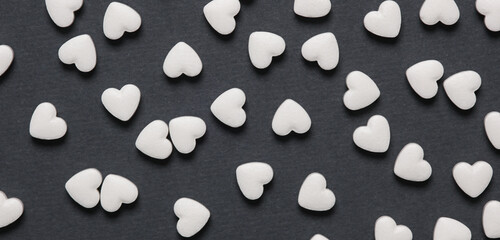 Naklejka premium Pills in the form of hearts on a gray background. Treatment of heart disease