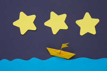 Scene of origami boat in the paper ocean against the background of night sky with stars. Children's creativity