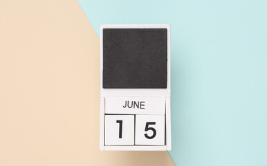 White wooden calendar with the date june 15 on a blue beige background. Top view
