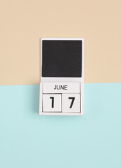 White wooden calendar with the date june 17 on a blue beige background. Top view