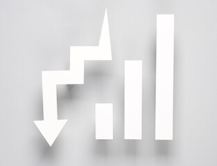 Paper-cut columns of a chart tending upwards and drop arrow on gray background. Economic, analytics, business concept