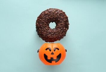 Chocolate donut and halloween bucket on blue background. Halloween concept. Trick or Treat