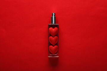 Perfume bottle with hearts on a red background. Beauty concept, valentine's day