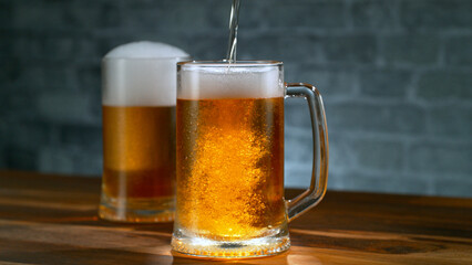 Pouring beer into glass on old wooden table, close-up