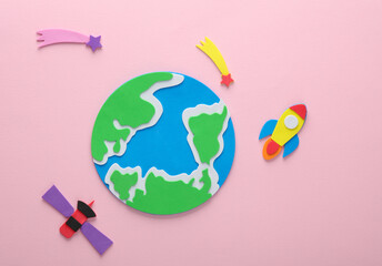 Handmade, children's art. Rocket with comets and planet earth, satellite on pink background. Space exploration