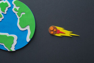Handmade, children's art. Planet earth with a flying meteorite on a gray background.