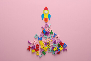 Toy ocket and letters on pink background. Back to school. Education concept. Flat lay