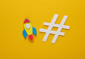 Paper-cut hashtag with rocket on yellow background. Startup concept