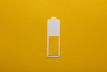 Paper-cut battery with an average charge level on a yellow background
