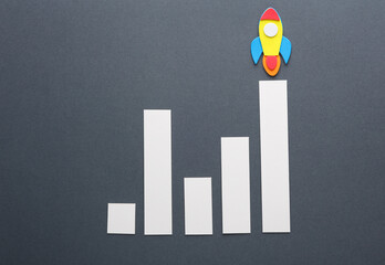 Space rocket with bar graph on a gray background. Startup, business concept