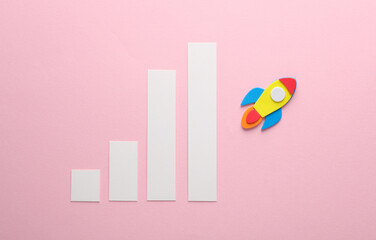 Space rocket with bar graph on a pink background. Startup, business concept