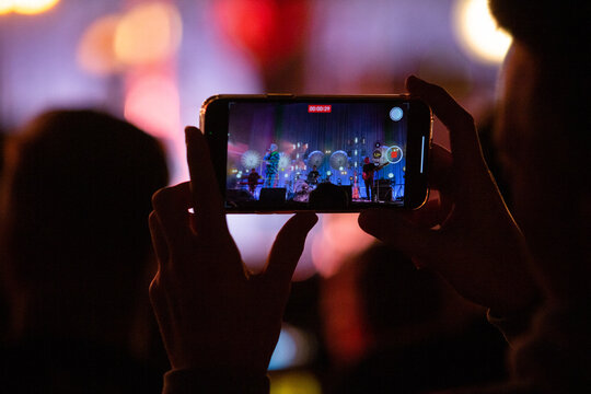 Kobieta nagrywająca koncert telefonem kom&oacute;rkowym. Nagrywanie koncertu telefonem.