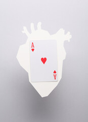 Paper-cut heart with ace of hearts card on gray background