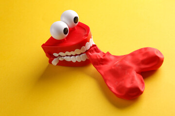 Joke jaw inflates red heart shaped balloon on Yellow background. Love concept